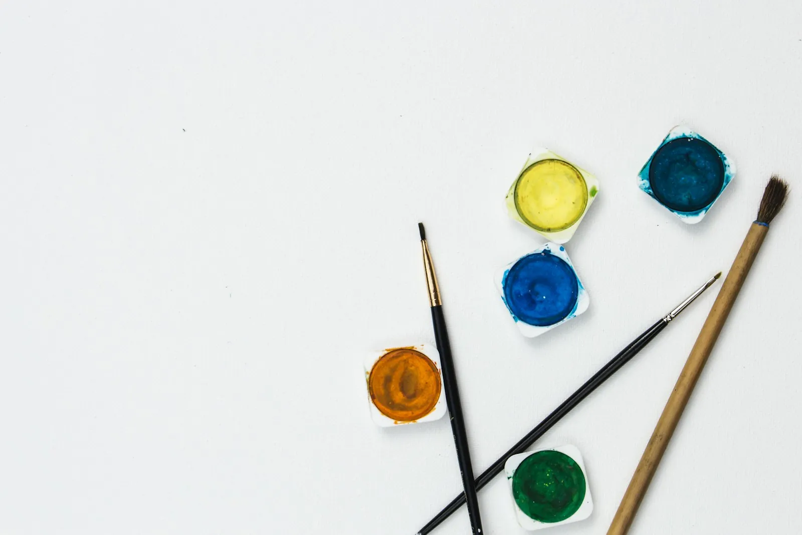 Paint pans and brushes laid out on a white surface